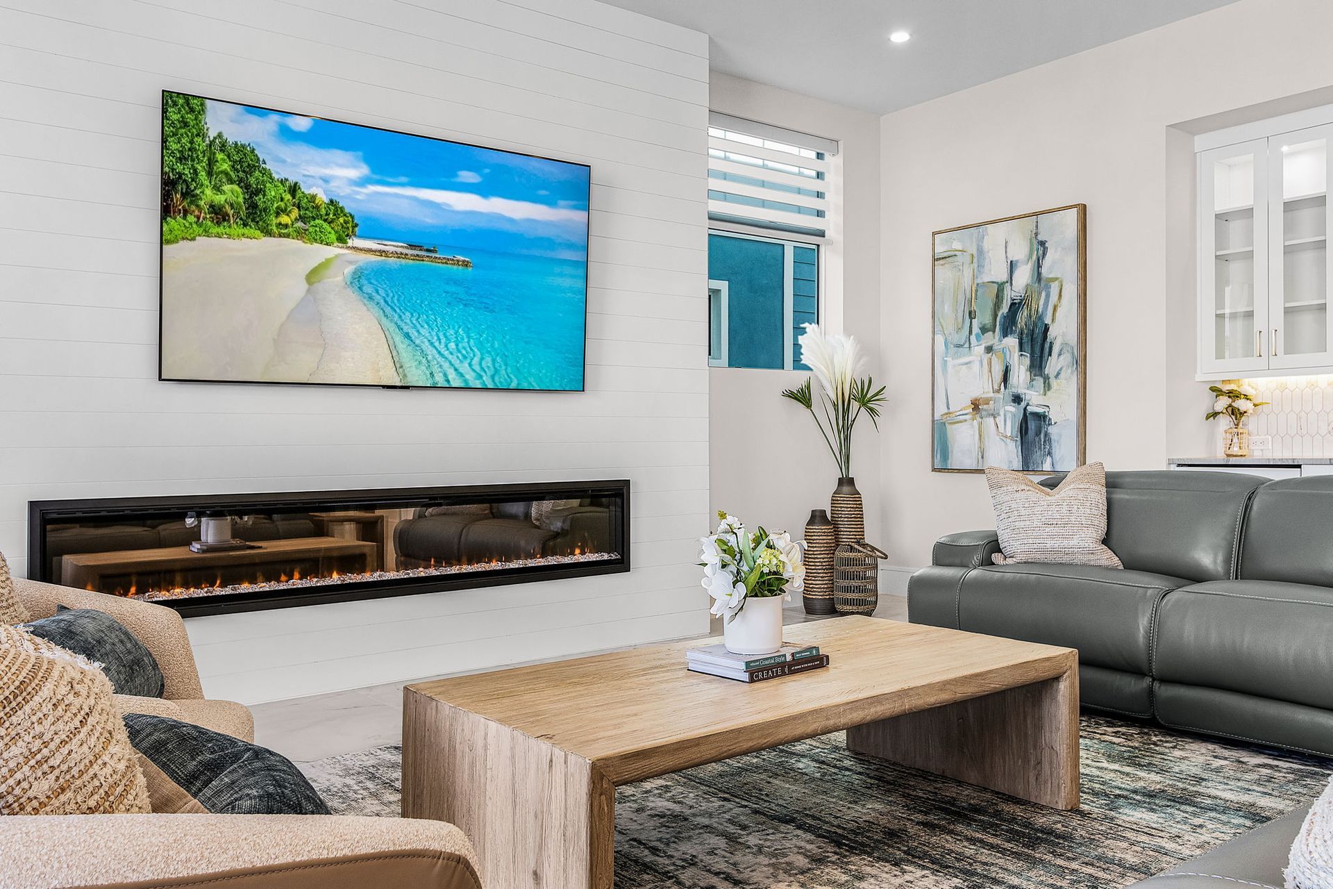 Living room with a wall-mounted TV over an electric fireplace, sofa, and wood coffee table.