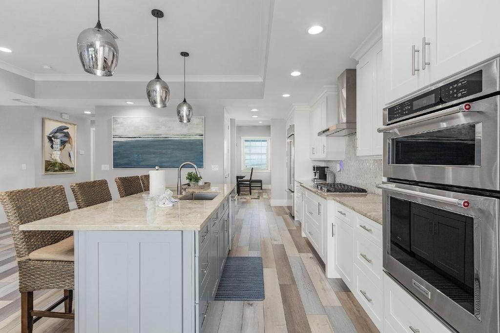 Spacious modern kitchen with island, pendant lights, and stainless steel appliances.