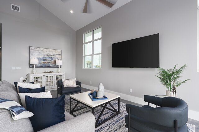 Modern living room with gray walls, large TV, sofa, chairs, and coffee table.