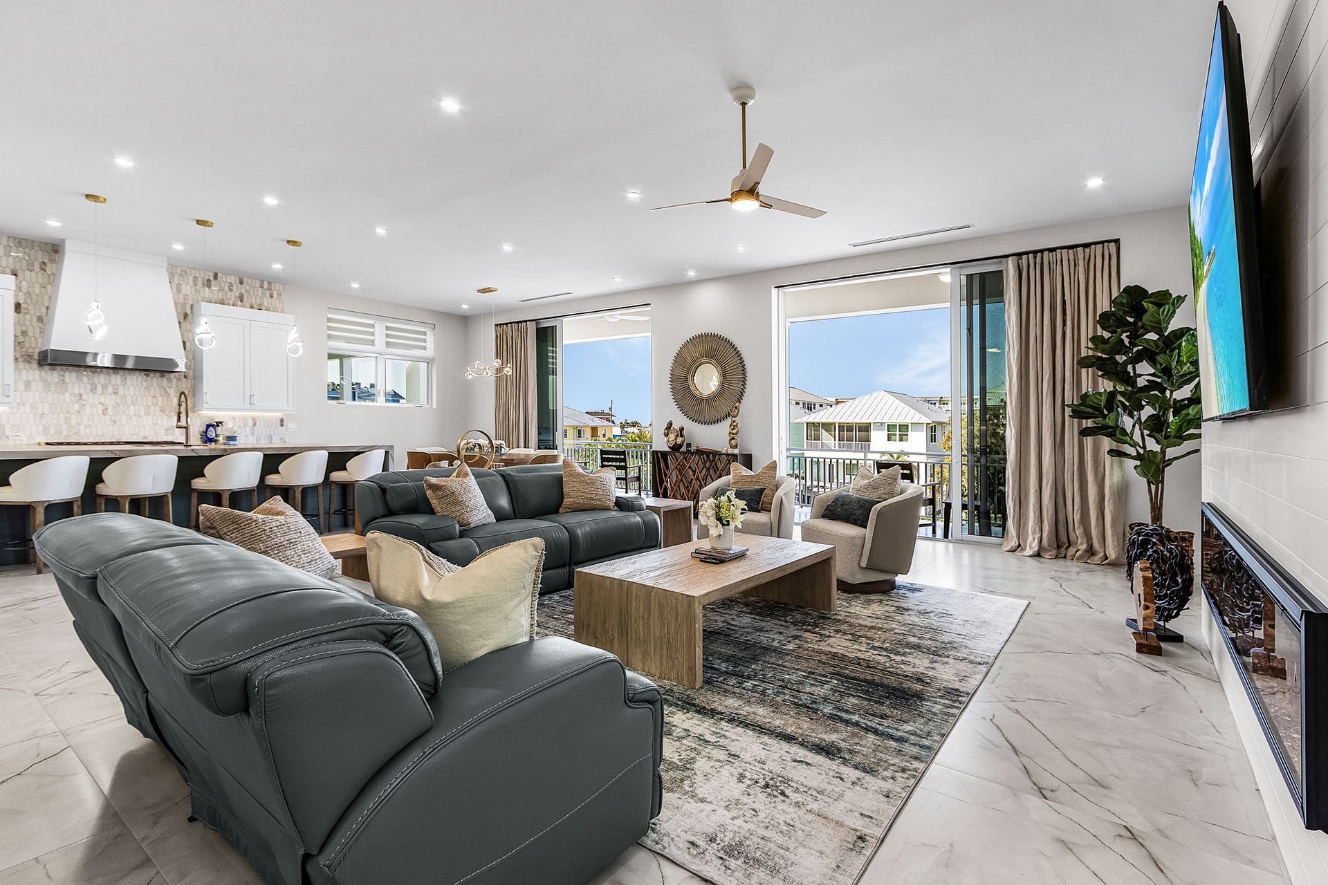 Open-concept living room with gray furniture, large windows, and a view of a neighborhood.