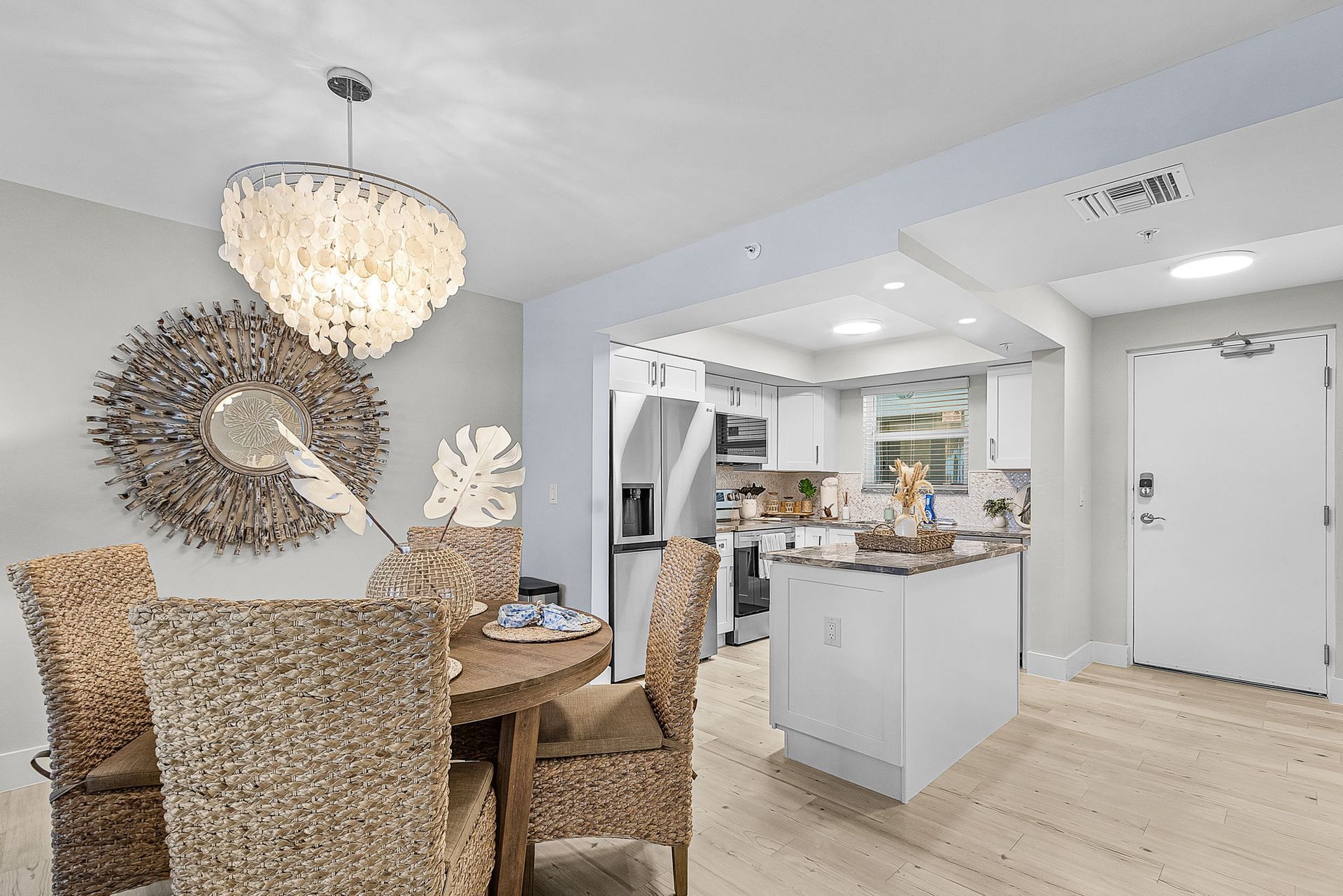 Dining room with chandelier, open to kitchen and entryway. Neutral colors and natural light.