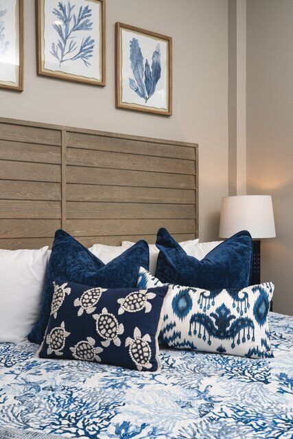 Bedroom with blue and white bedding, pillows, art, and a wooden headboard.