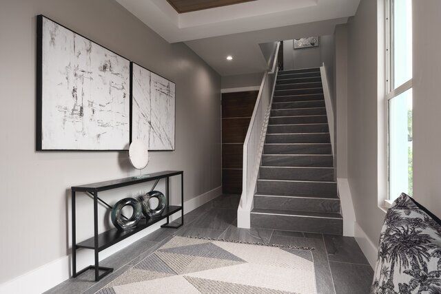 Hallway with gray walls, staircase, modern art, console table, geometric rug.