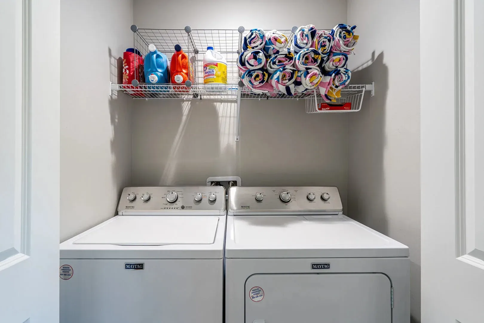 Laundry room with washer and dryer, shelves holding laundry supplies.