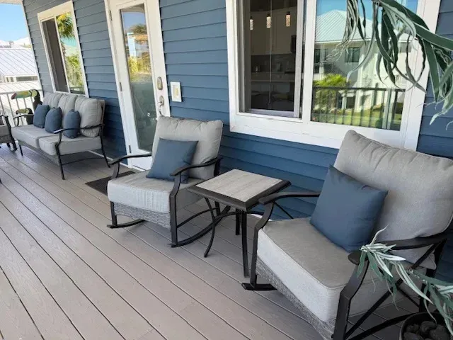 Outdoor porch with blue siding, gray furniture, and square side table.