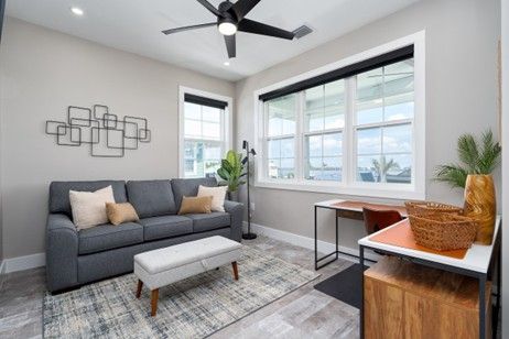 Cozy living room with gray sofa, wooden desk, and large windows.