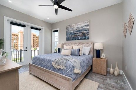 Bedroom with bed, art, and French doors leading to a balcony. Blue and beige color scheme.