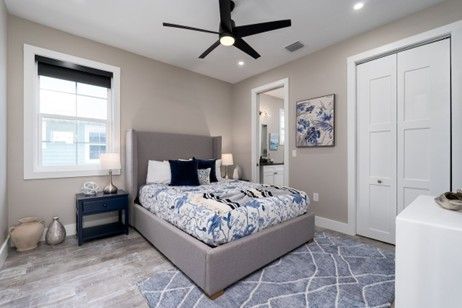 Bedroom with gray walls, bed, blue rug, nightstand, ceiling fan, and white closet.