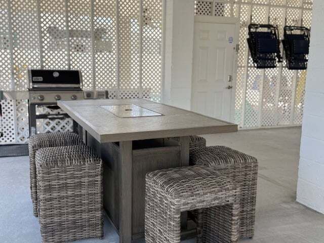 Outdoor seating area with a table, stools, grill, and decorative lattice walls.