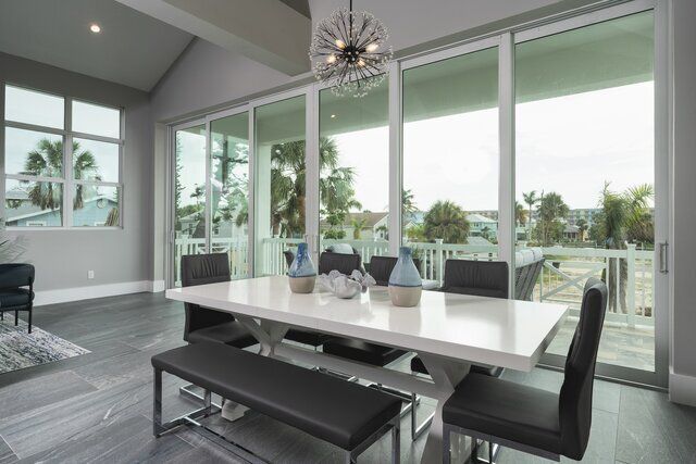 Dining room with white table, black chairs, and large glass doors overlooking a balcony.