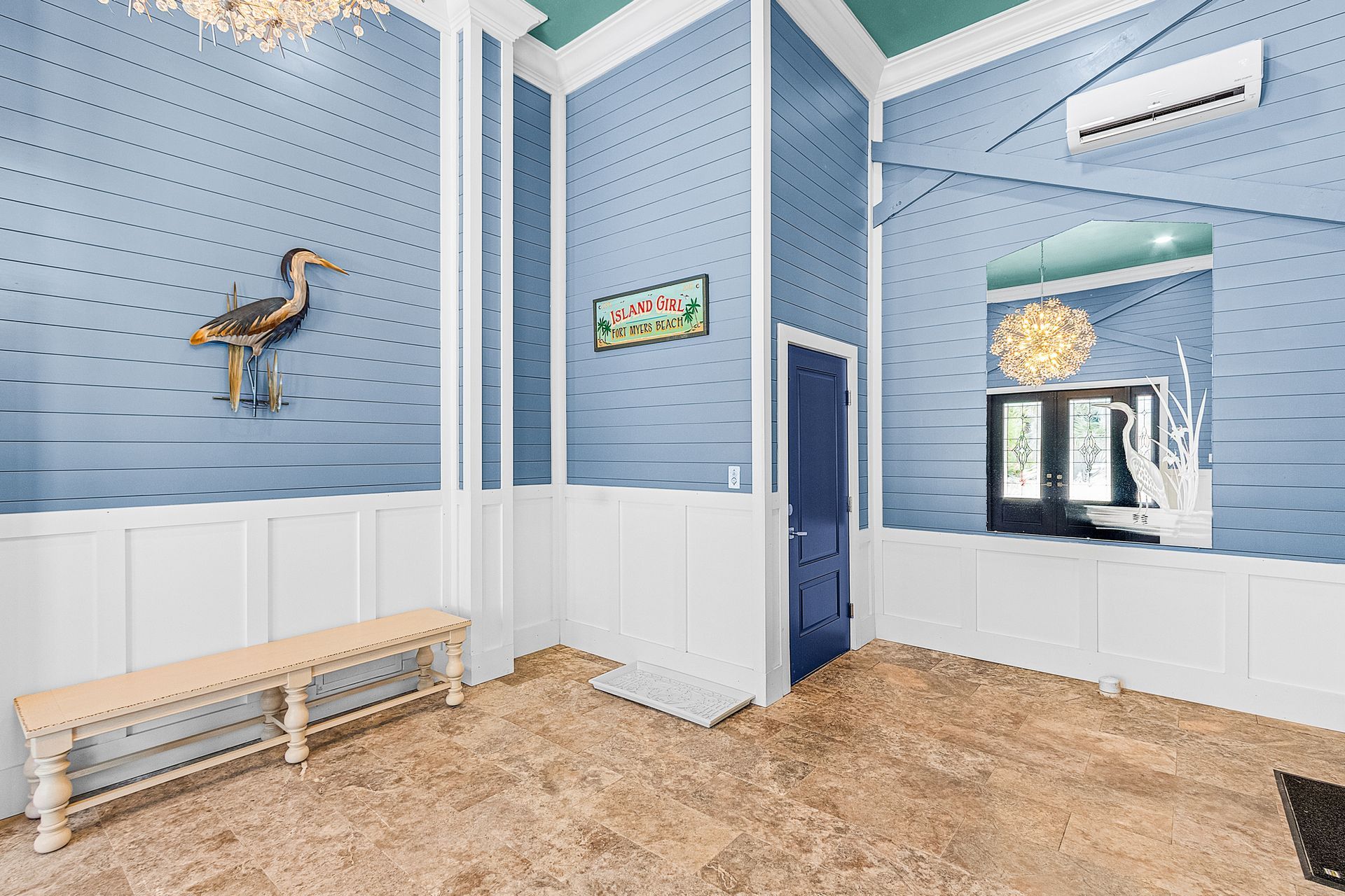 Blue-walled room with white wainscoting, bench seating, bird decor, and a doorway to another bright room