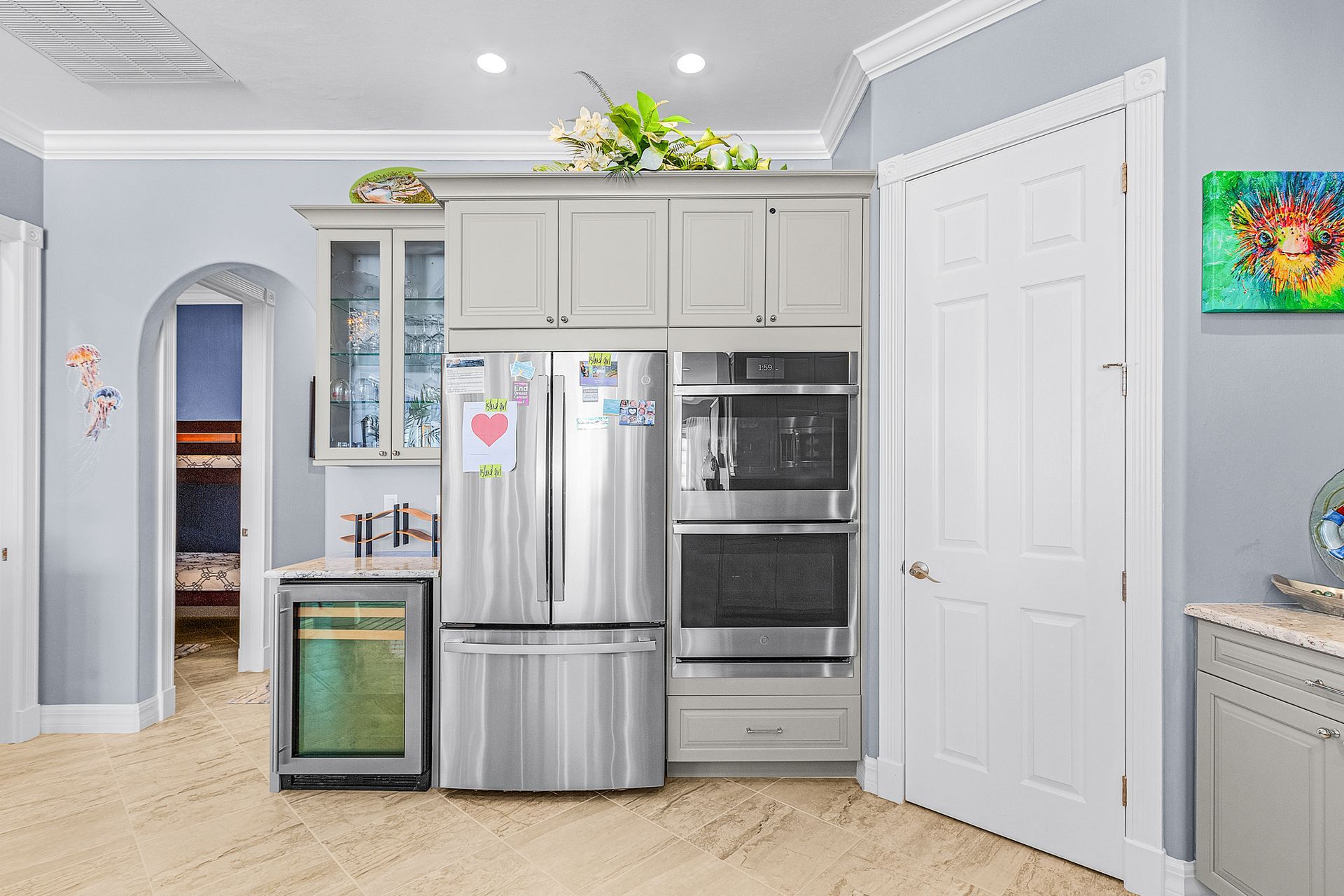 Modern kitchen with stainless steel appliances, white cabinets, and light gray walls