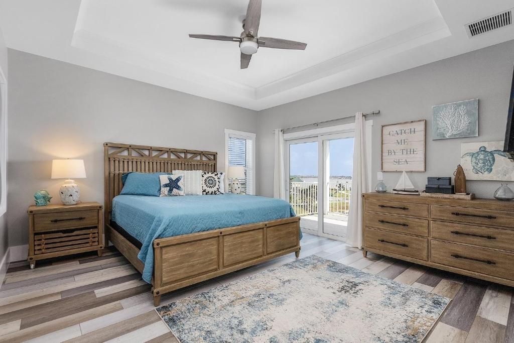 Coastal bedroom with wooden furniture, blue accents, and a ceiling fan.