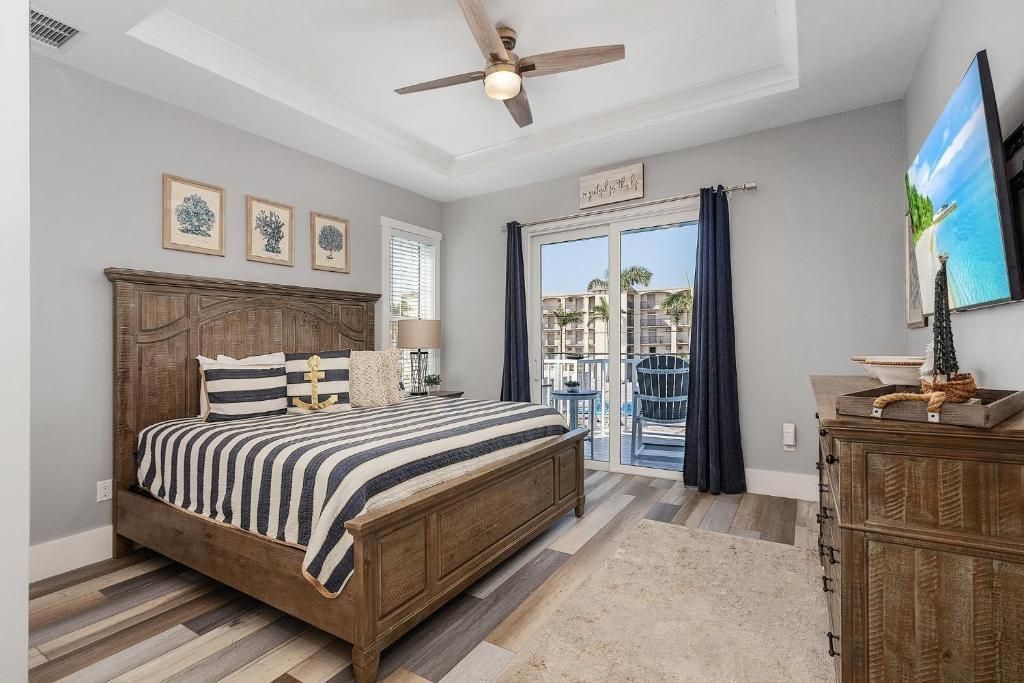 Bedroom with a wooden bed, blue and white striped bedding, and a sliding glass door leading to a balcony.