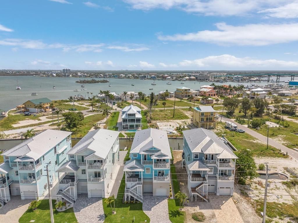 Row of colorful houses by the water, with a town and boats in the background on a sunny day.