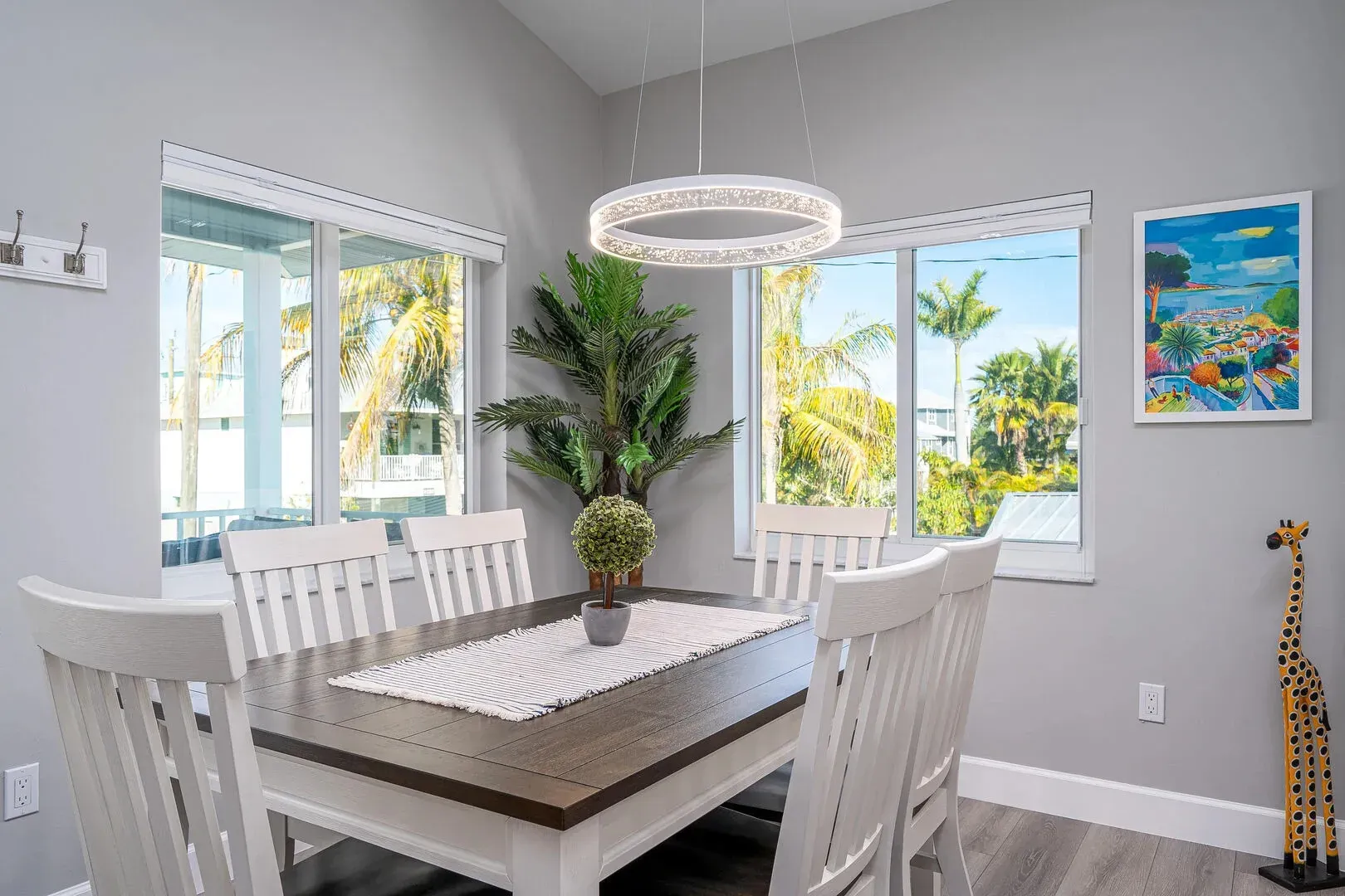 Dining room with table, chairs, windows, and decorative chandelier.