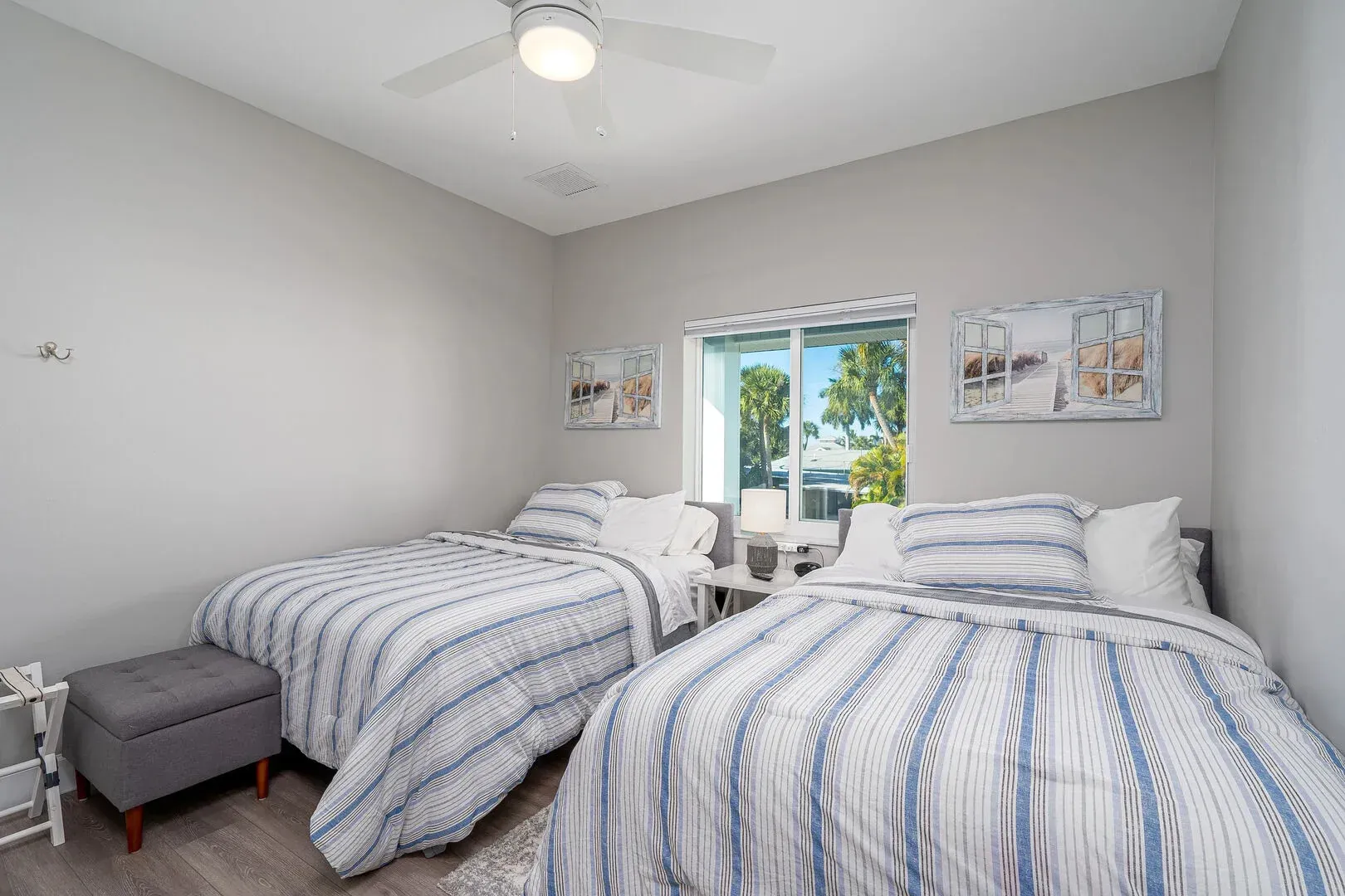 Bedroom with two twin beds, blue and white striped bedding, window, gray walls, ceiling fan.