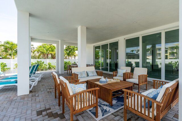 Patio with wood furniture, blue accents, brick floor, under a white-columned awning.
