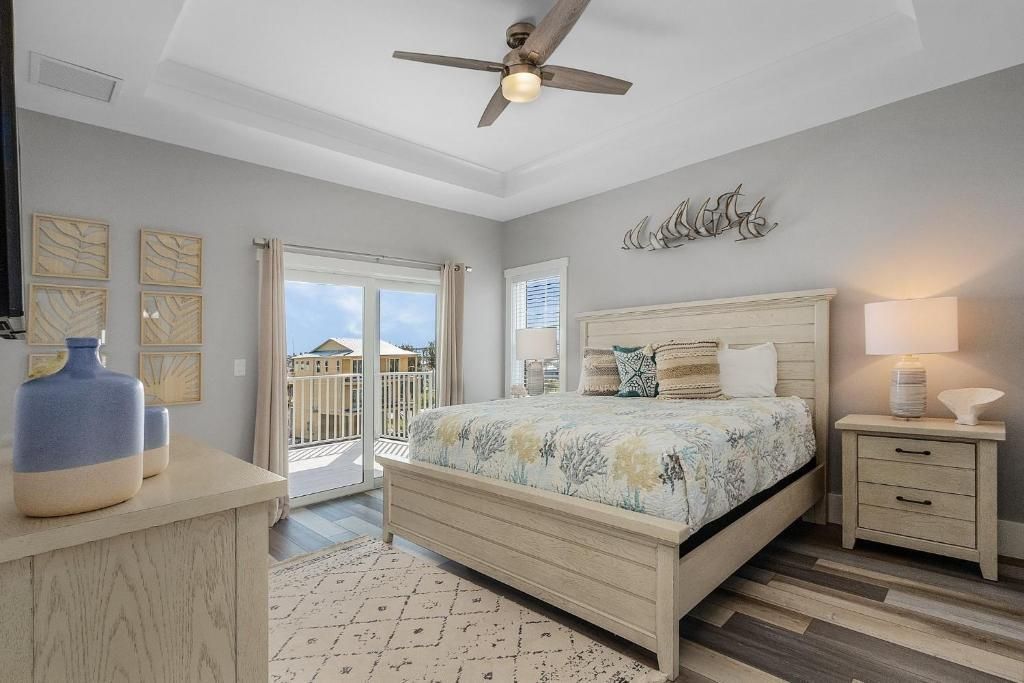 Bedroom with bed, balcony doors, gray walls, light-colored furniture, and decorative accents.