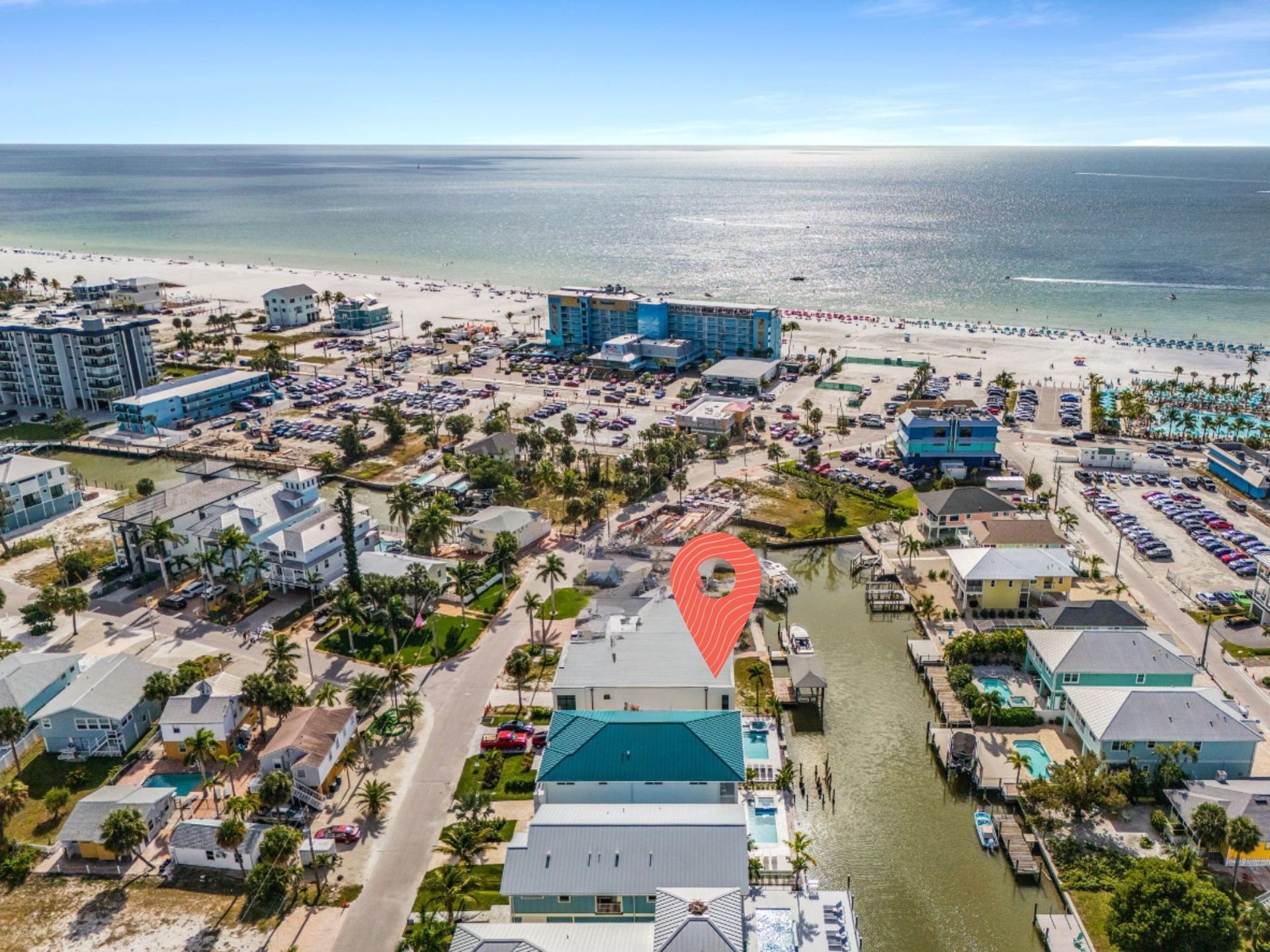 Aerial view of beachfront homes with a navigation marker. Beach with people in the background.