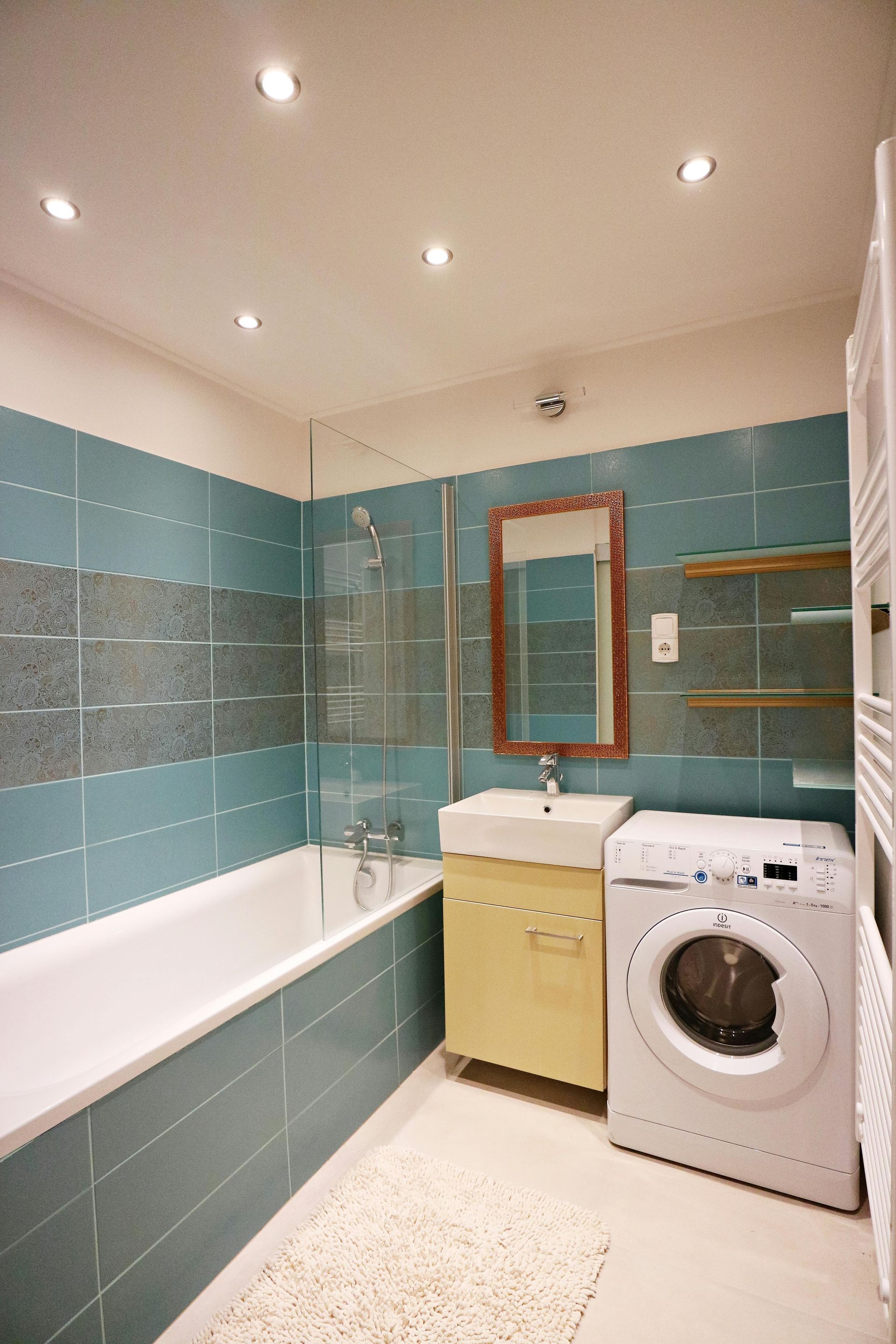 green turqoil tiled bathroom with washing machine, sink and bathtub
