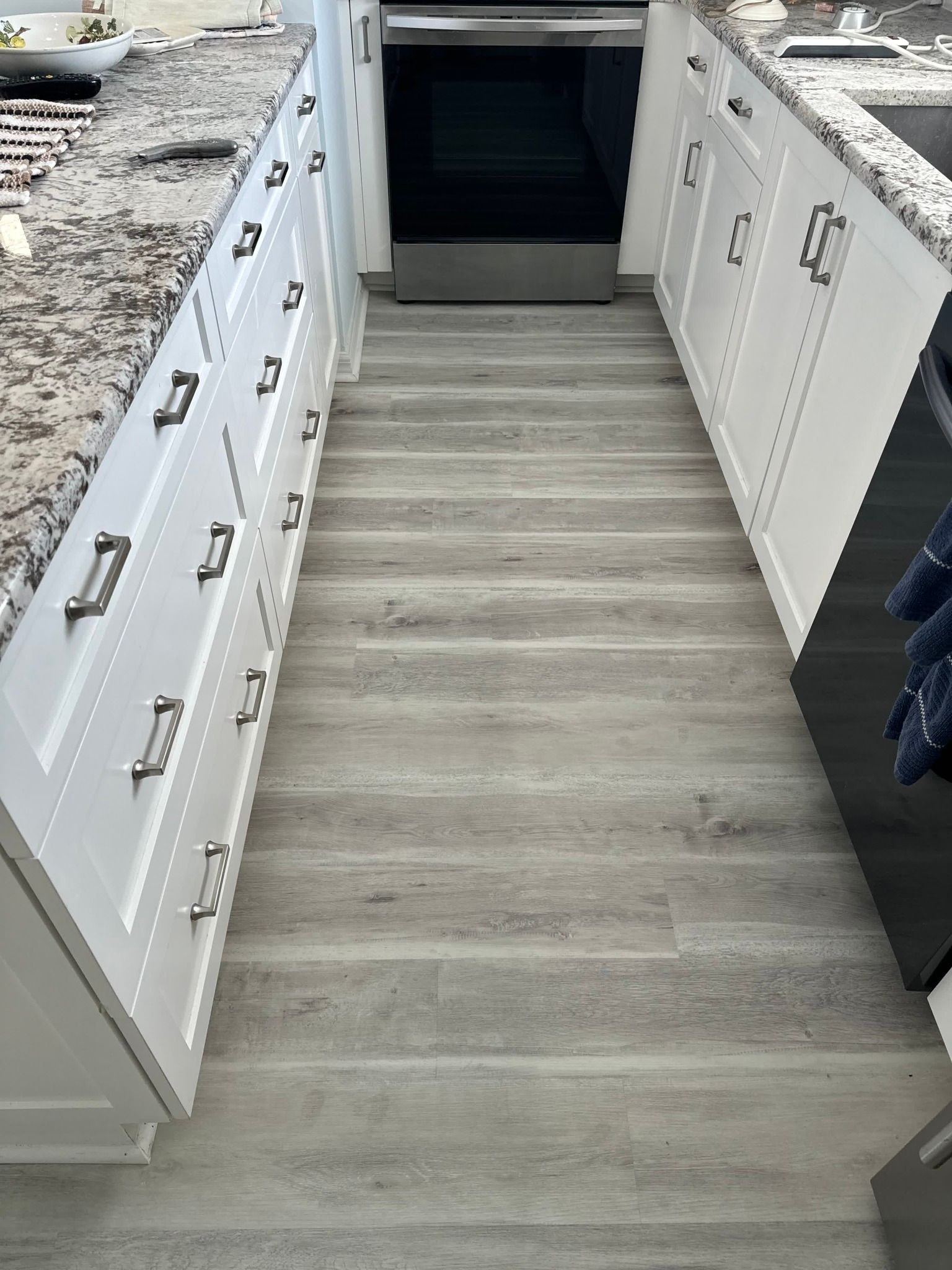 A kitchen with white cabinets and a wooden floor.
