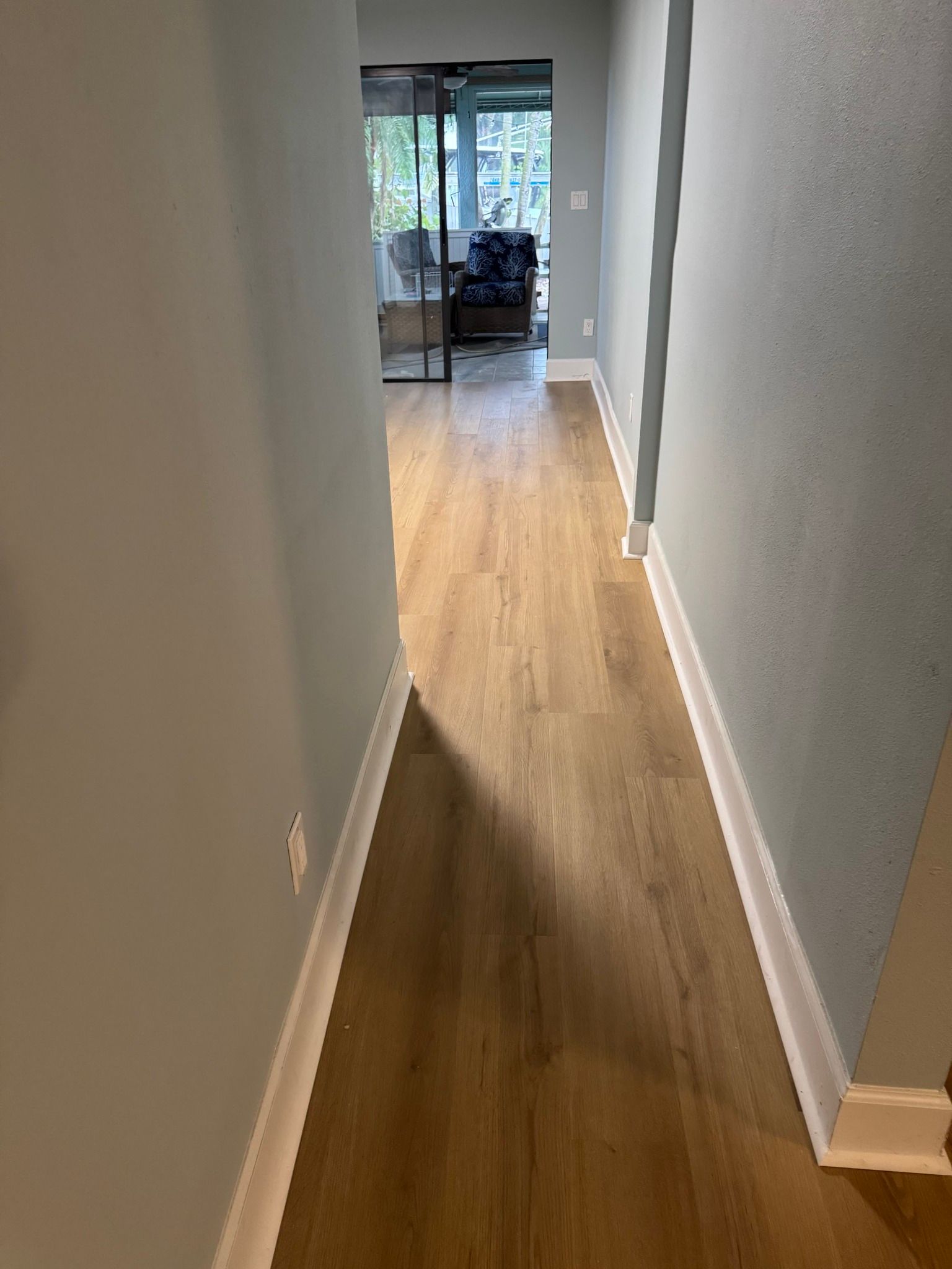 A hallway with hardwood floors leading to a living room.