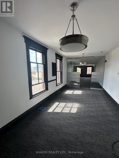 Empty office interior with black trim around windows and dark carpet. A chandelier hangs from the ceiling.