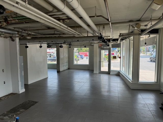 A large empty room with a lot of windows and pipes.