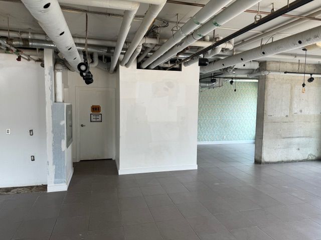 A large empty room with pipes hanging from the ceiling.