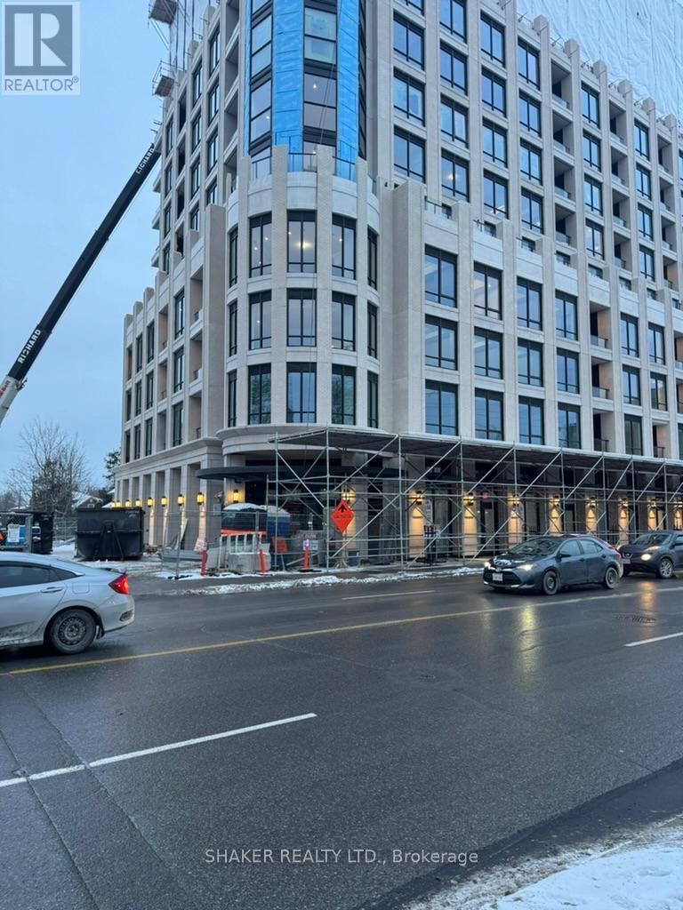Modern high-rise building under construction with scaffolding. Cars on the wet street.