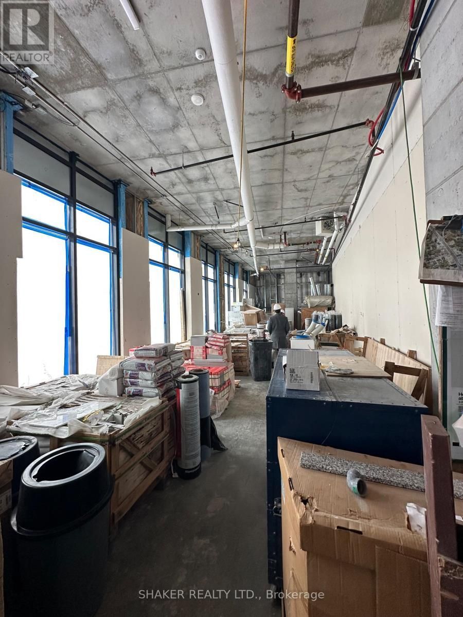 Interior of a construction site with materials, a worker, and large windows. Concrete ceiling and walls.