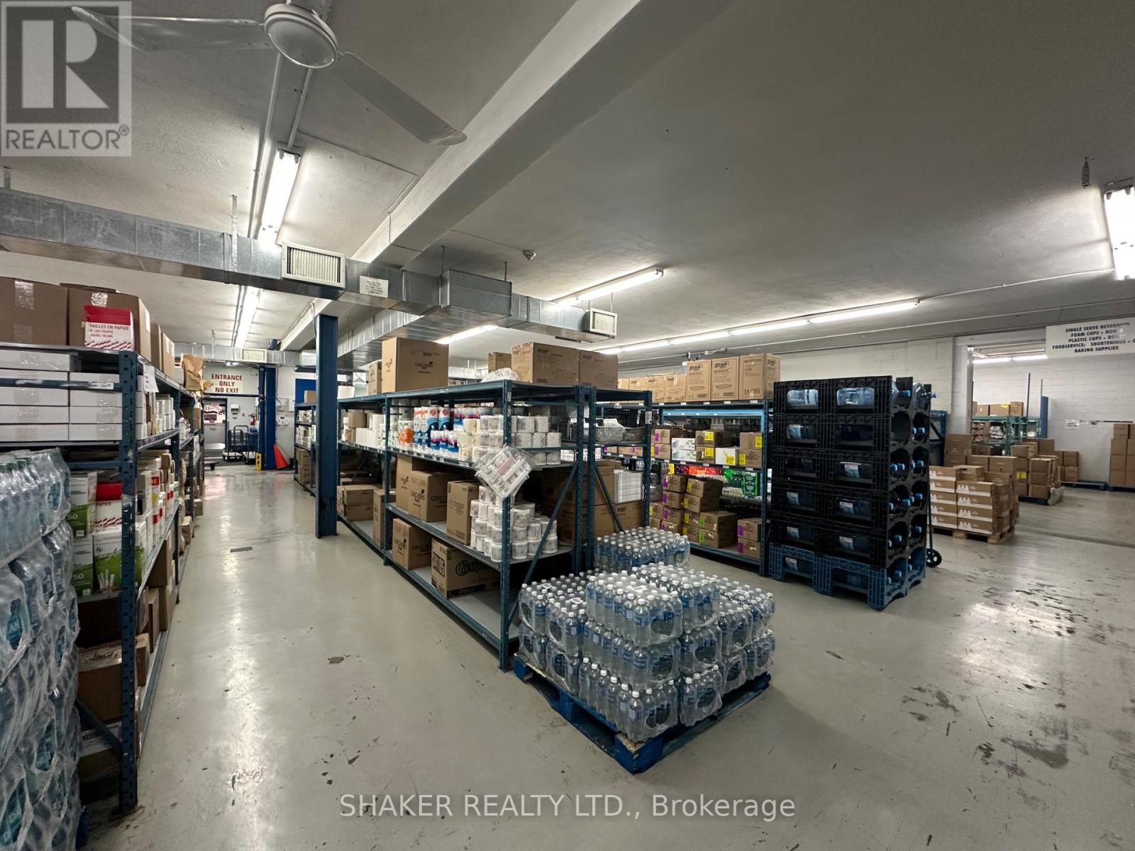 Warehouse interior with shelves of boxes, pallets of water bottles, and blue support beams.