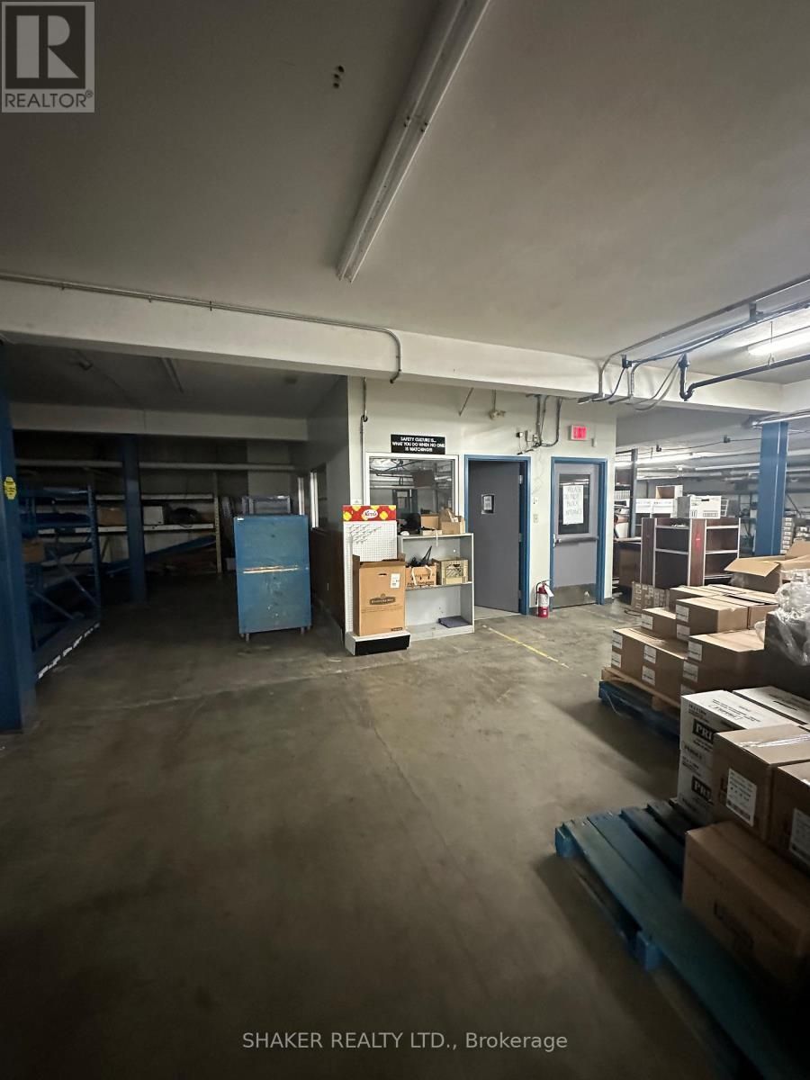 Warehouse interior with shelves, boxes, and a blue pallet. Fluorescent lighting.