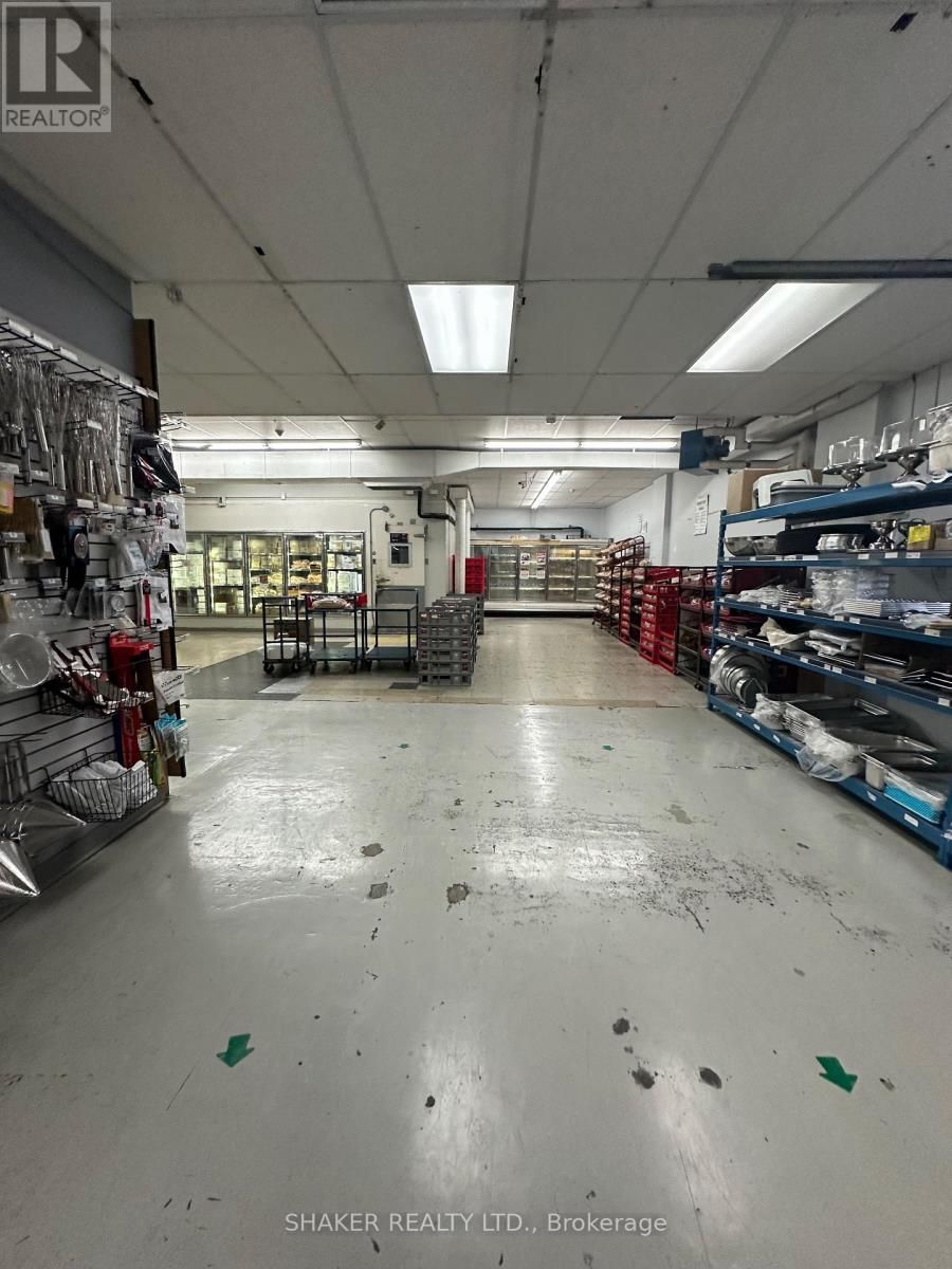 Warehouse interior with concrete floor, fluorescent lights, shelving, and merchandise.