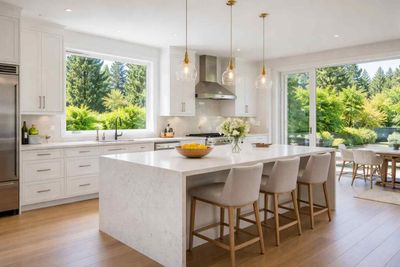 Bright, modern kitchen with white cabinetry, a large marble-topped island with three bar stools, and outdoor garden views.