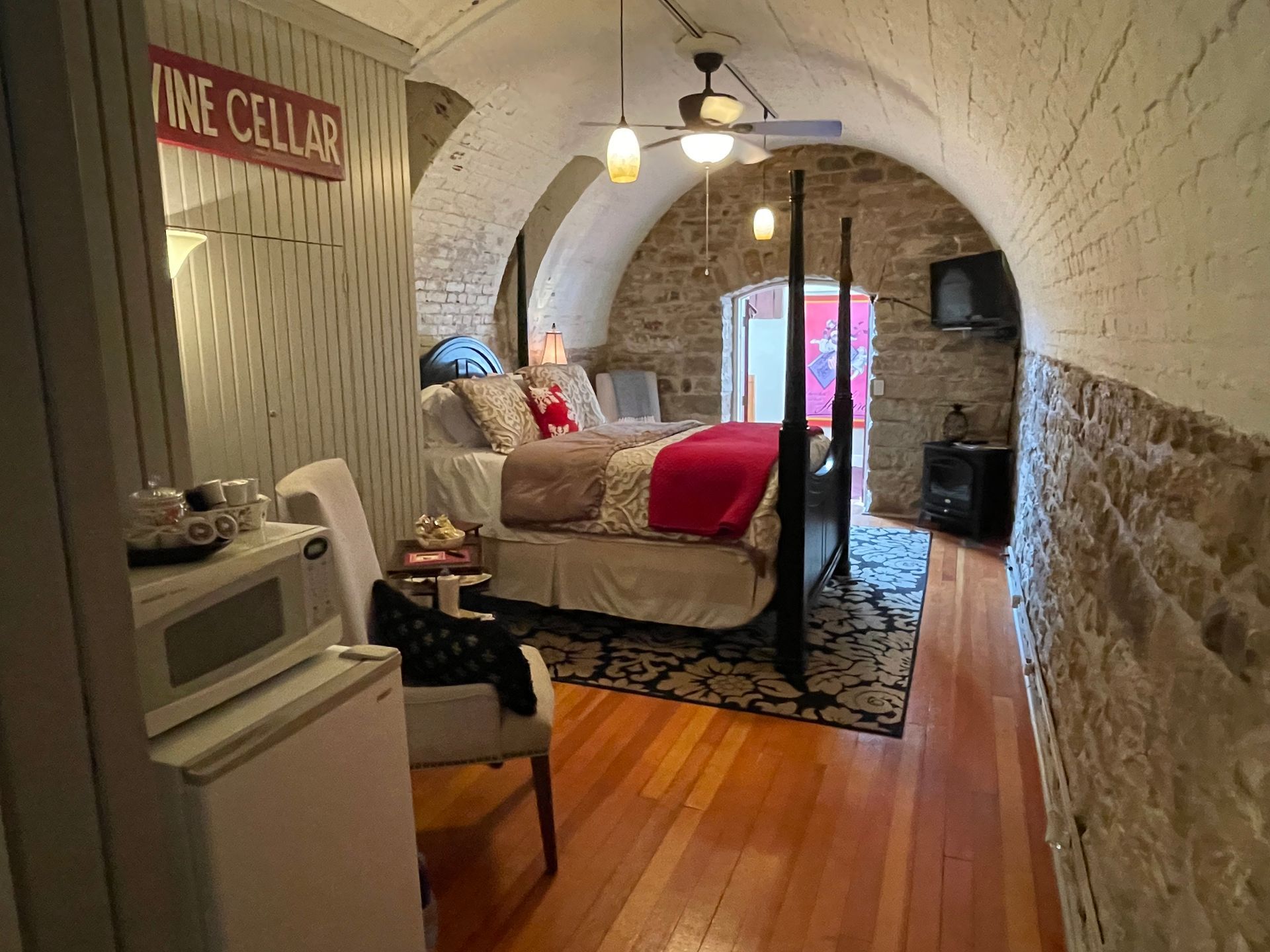 Bedroom in a stone archway with a four-poster bed, rug, and microwave.