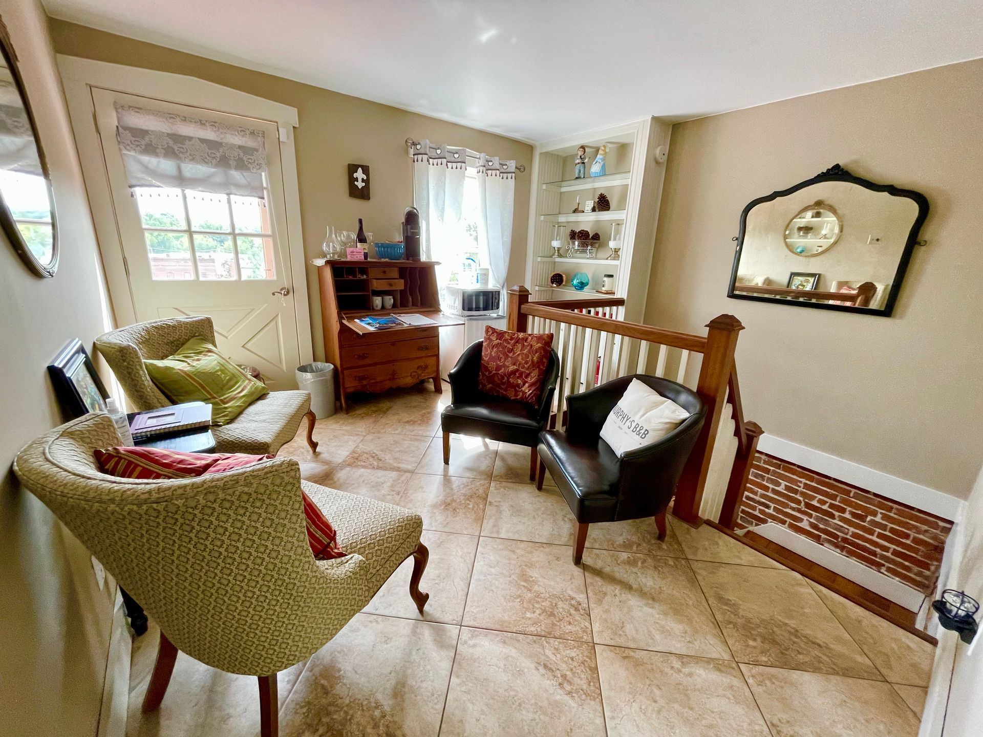Cozy room with seating, a desk, and a built-in bookshelf. Light colors, natural light, and a mirror.
