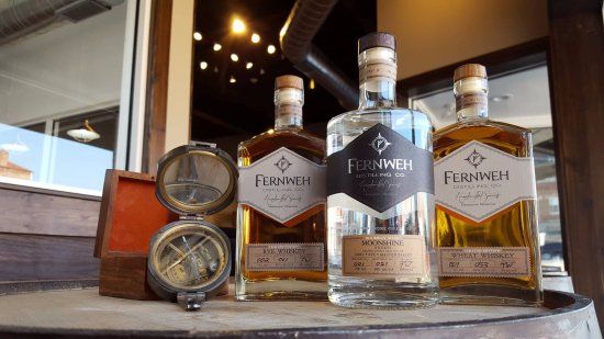Three bottles of spirits with a compass on a barrel in front of a window.