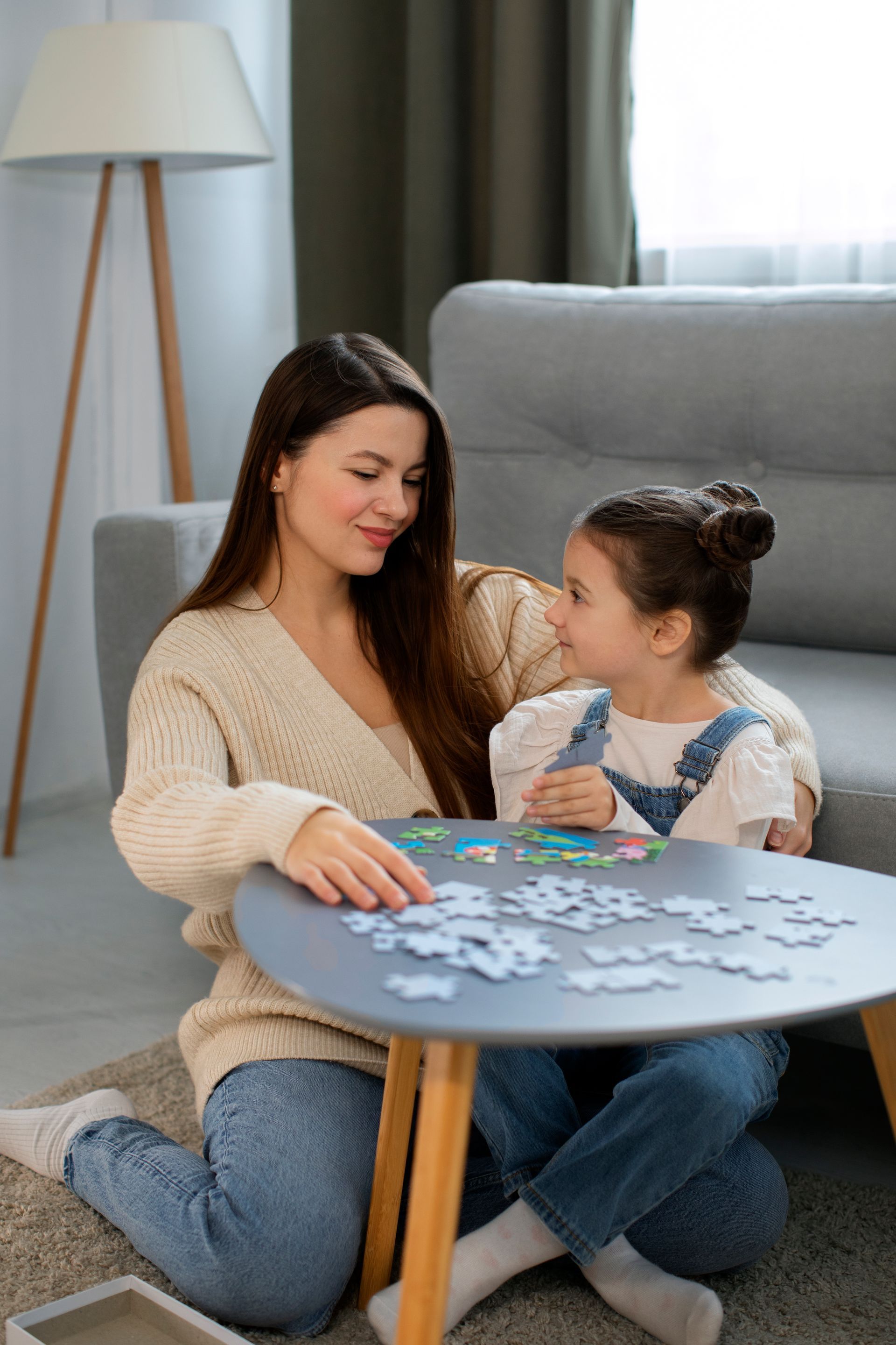 A woman is carrying a little girl on her shoulders in a field at sunset.