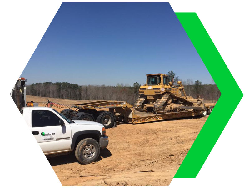 Bulldozer and white pickup truck at a dirt construction site under a blue sky