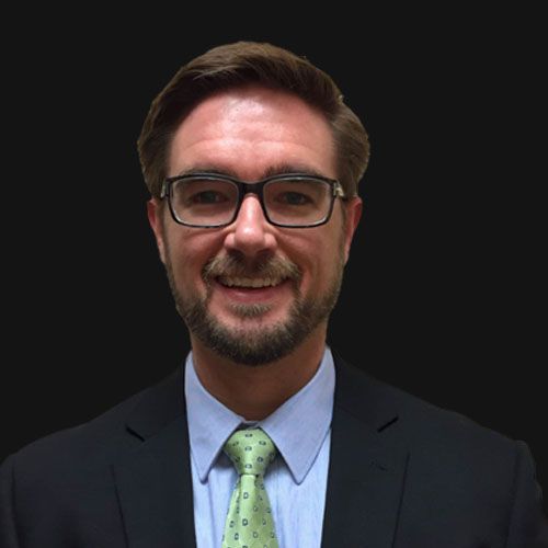 A smiling doctor in a lab coat with a stethoscope around his neck.