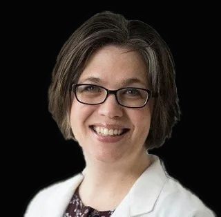 A smiling doctor in a lab coat with a stethoscope around his neck.
