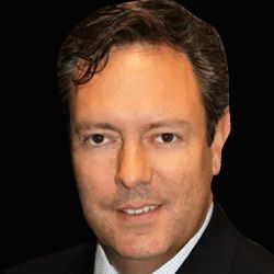 A smiling doctor in a lab coat with a stethoscope around his neck.