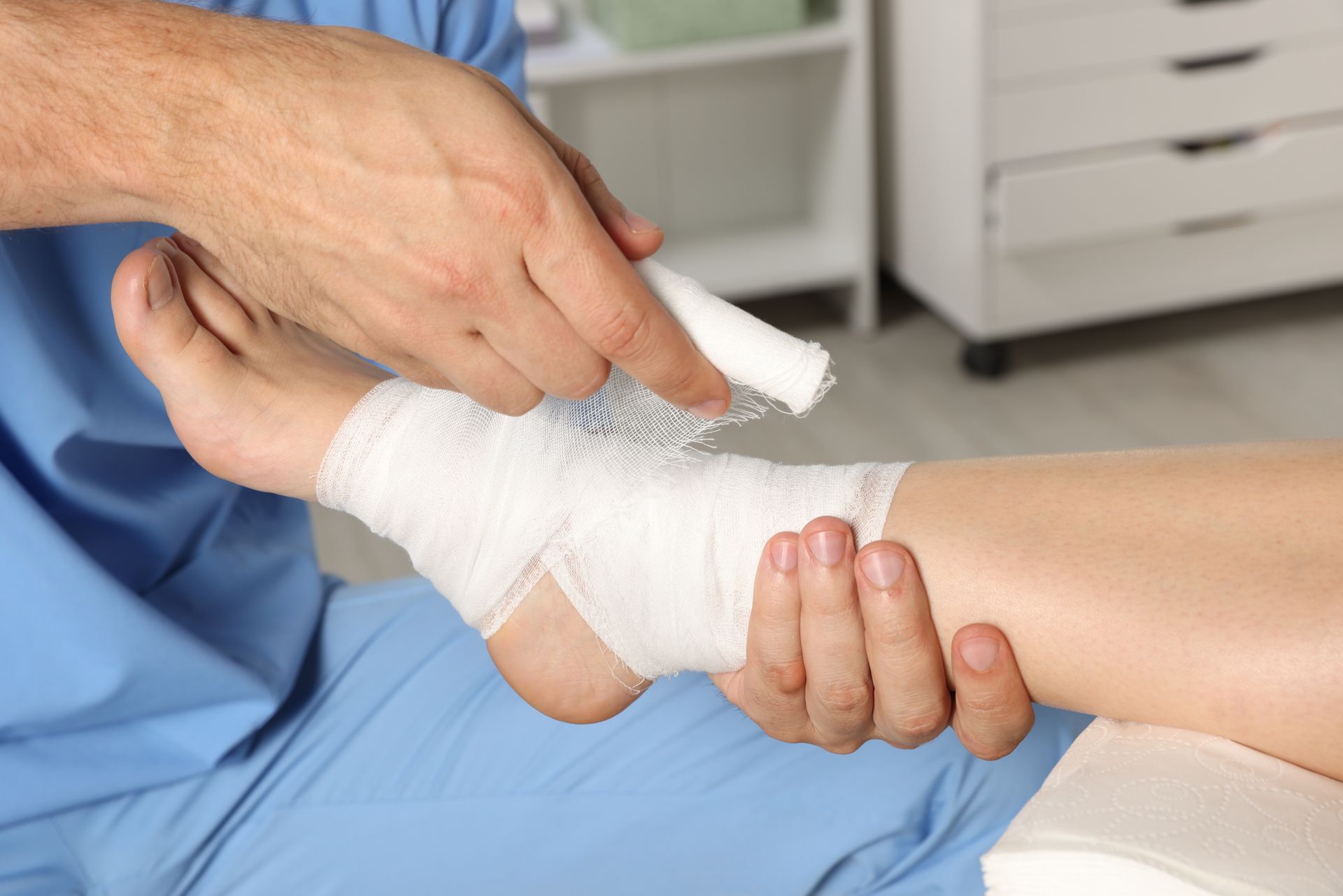 A person wrapping a white bandage around another person's ankle.