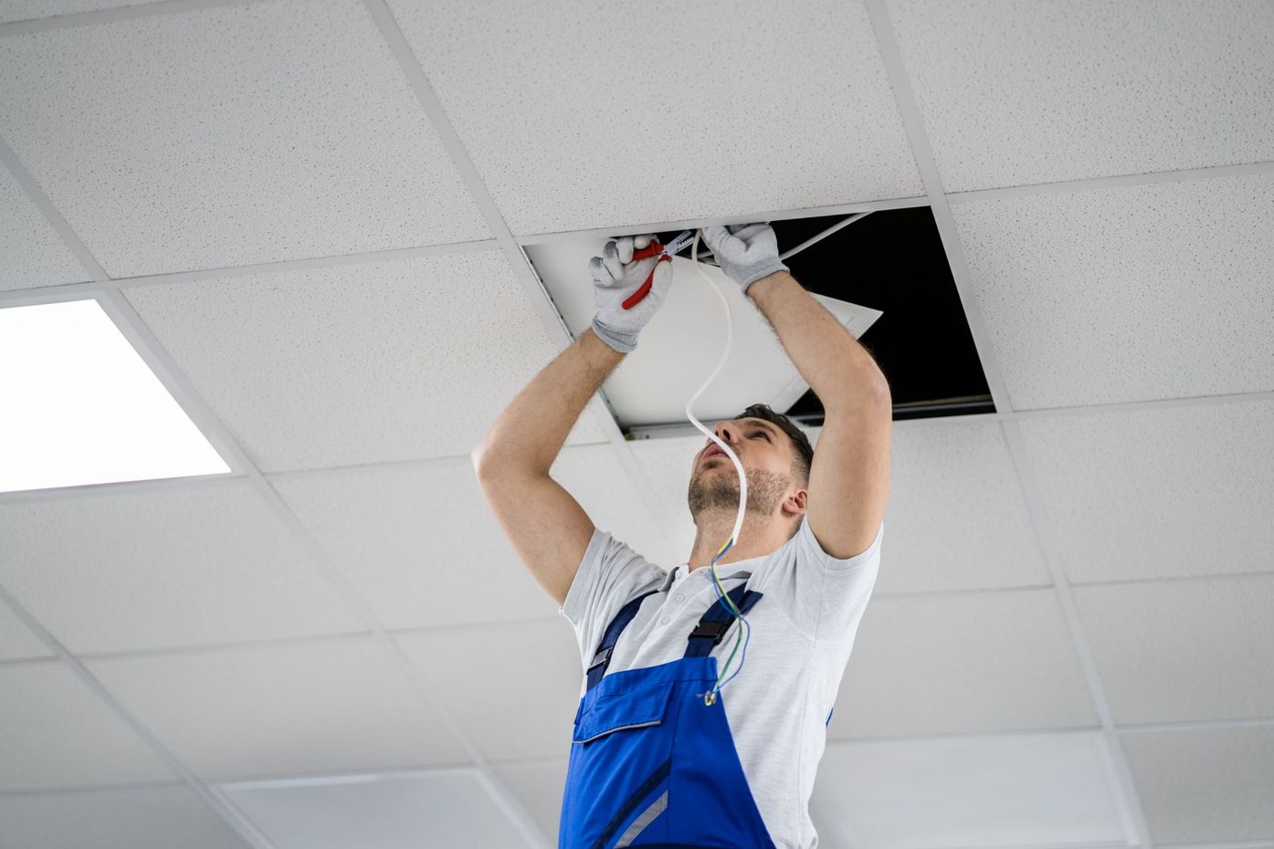 Man clipping wire in office ceiling