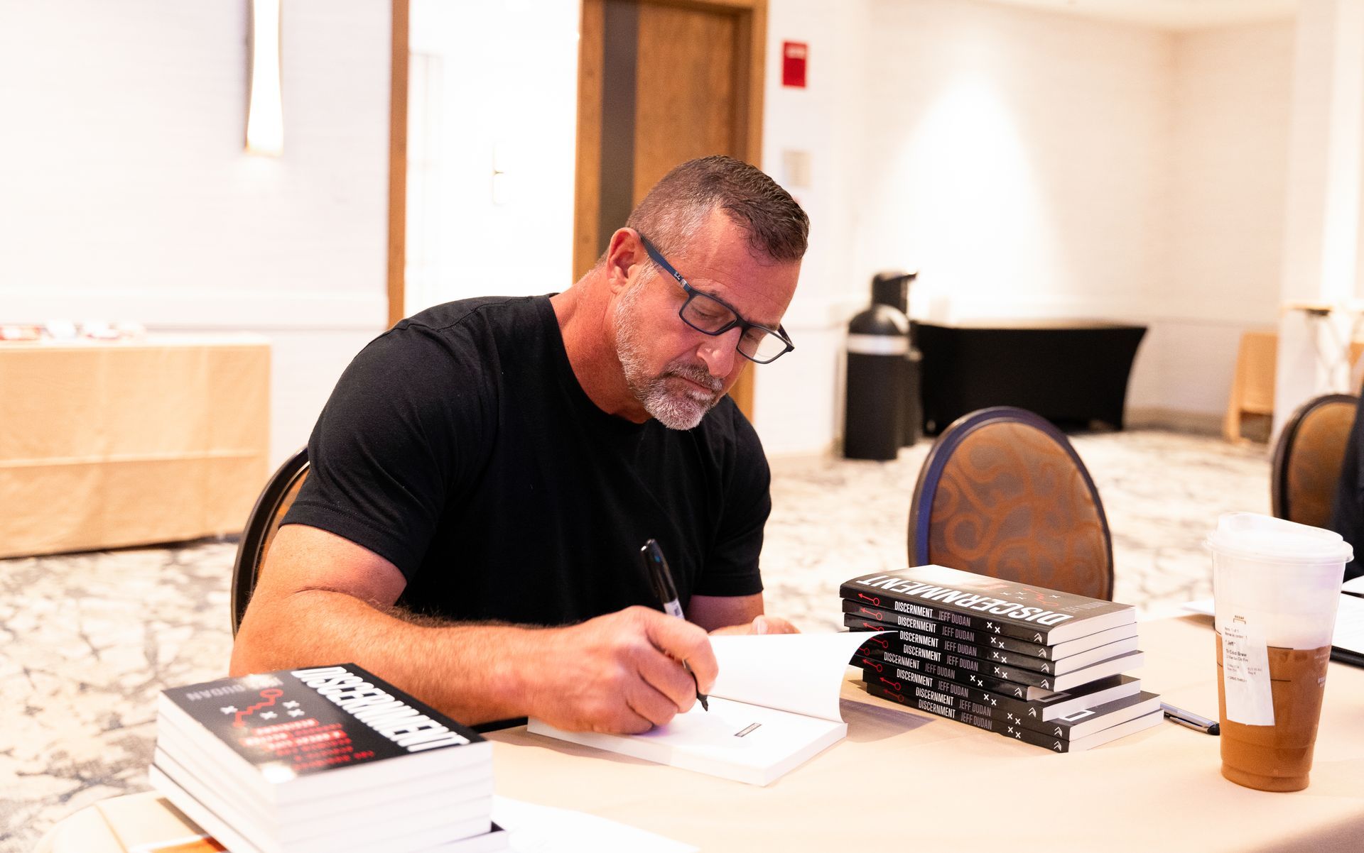 A man is sitting at a table signing books.