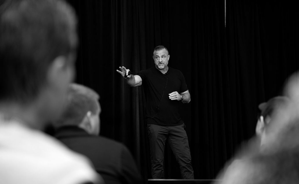 A man is giving a presentation to a group of people in a black and white photo.