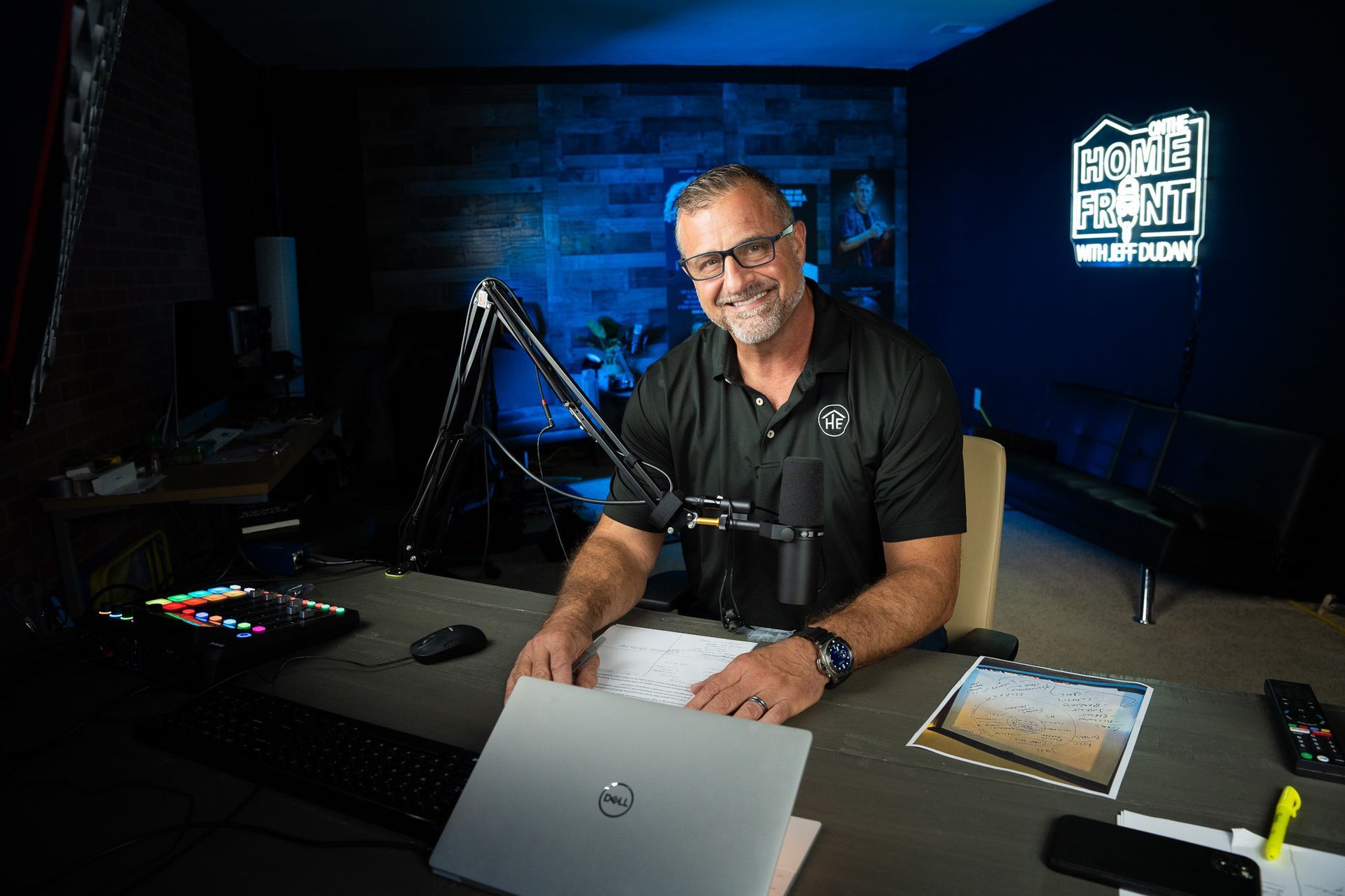 A man is sitting at a desk with a laptop and a microphone.