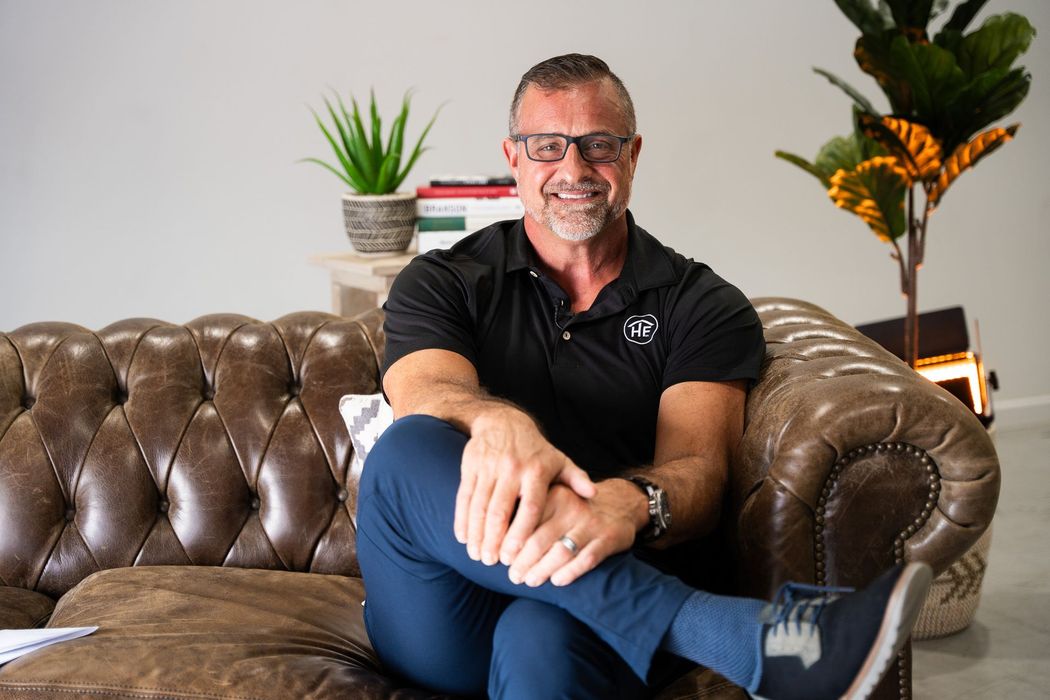 A man is sitting on a leather couch with his legs crossed.